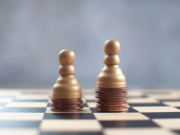 Two chess pieces balanced on a pile of coins, one higher than the other